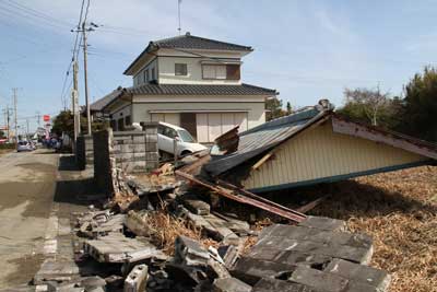 屋根しか残っていない家。後ろは津波で車が乗り上げてしまい斜めになっています。